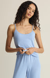 Woman wearing a light blue ribbed jumpsuit against a beige background