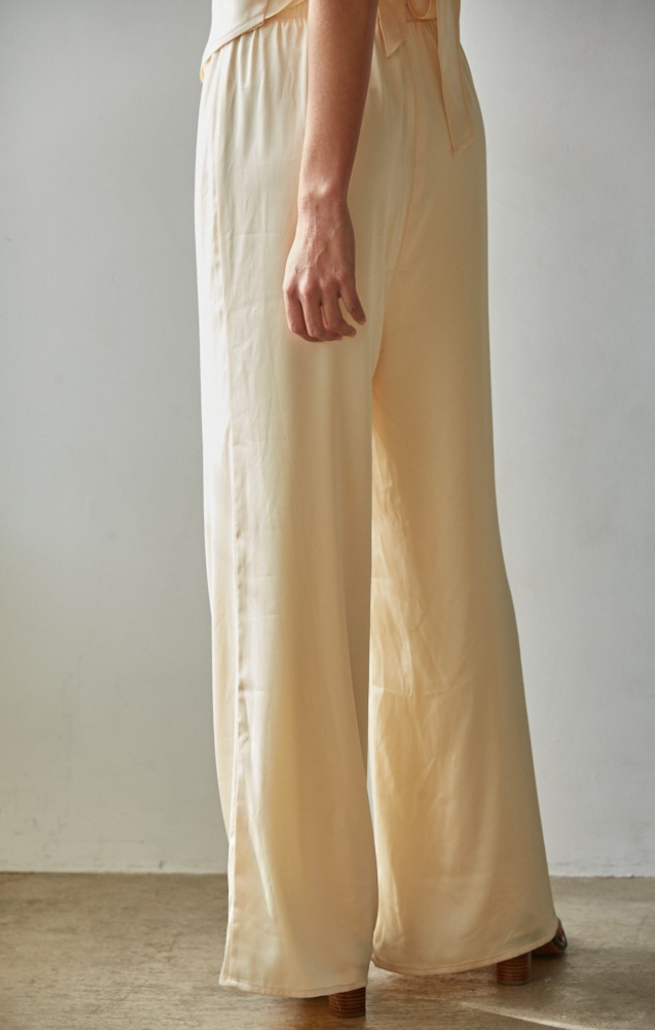 Beige wide-leg pants worn by a person against a plain background