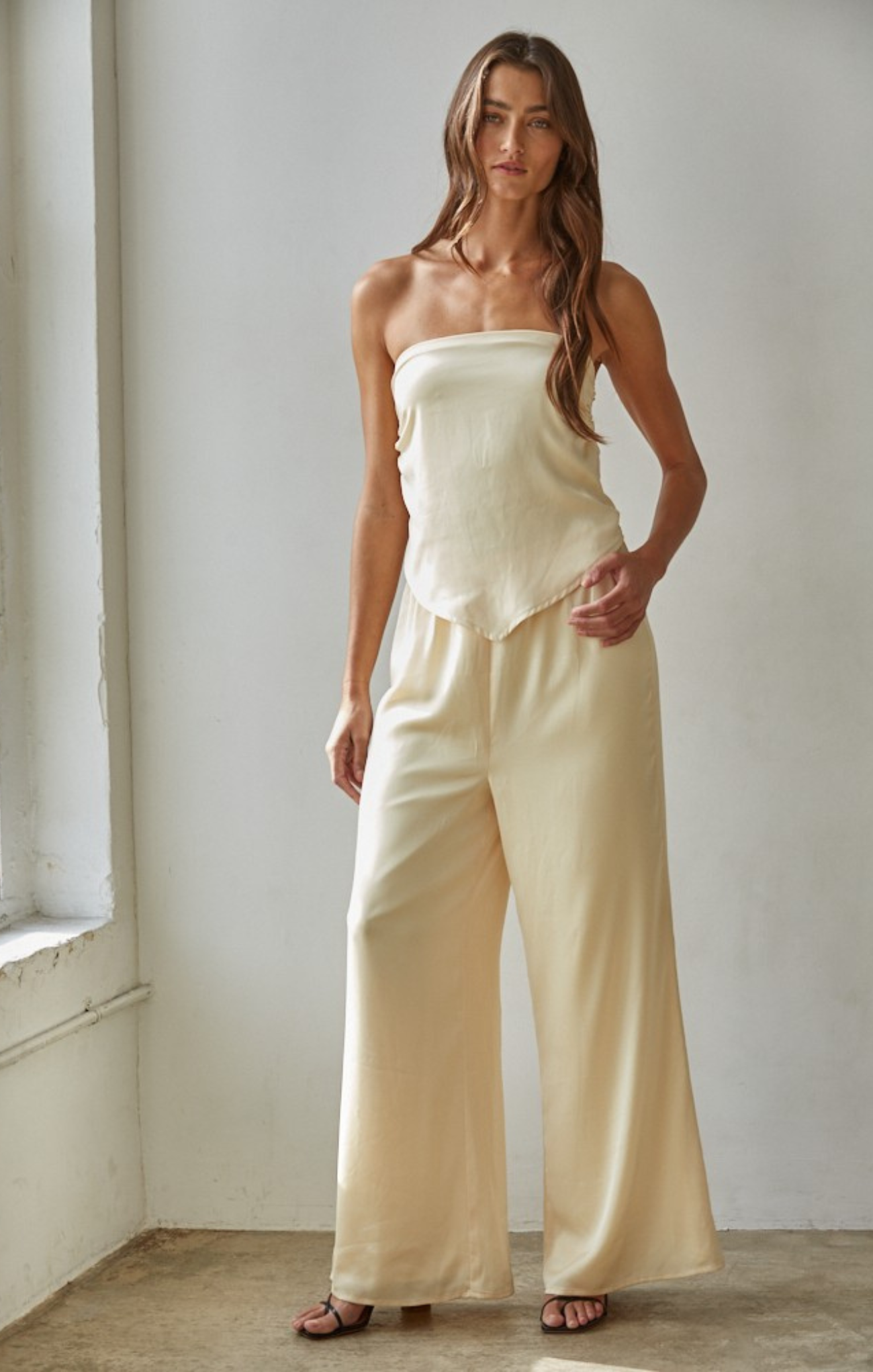 Woman wearing a strapless top and wide-leg pants in a minimalistic setting