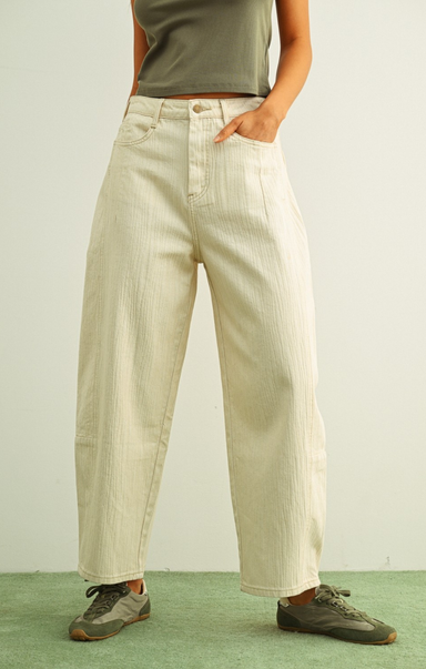 Person wearing beige wide-leg pants and a green top on a plain background