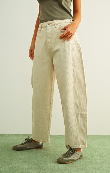 Person wearing beige wide-leg pants and green shoes on a plain background