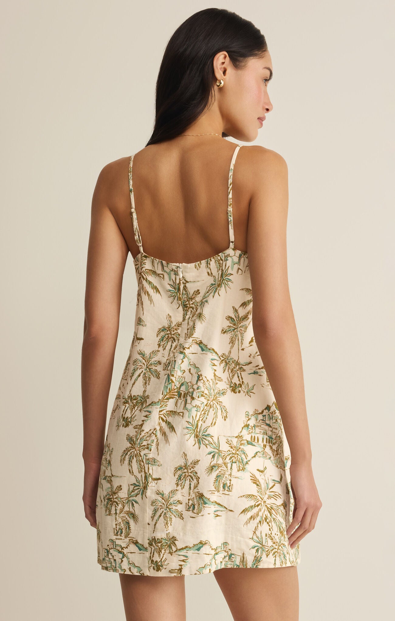 Woman wearing a floral dress with thin straps on a beige background