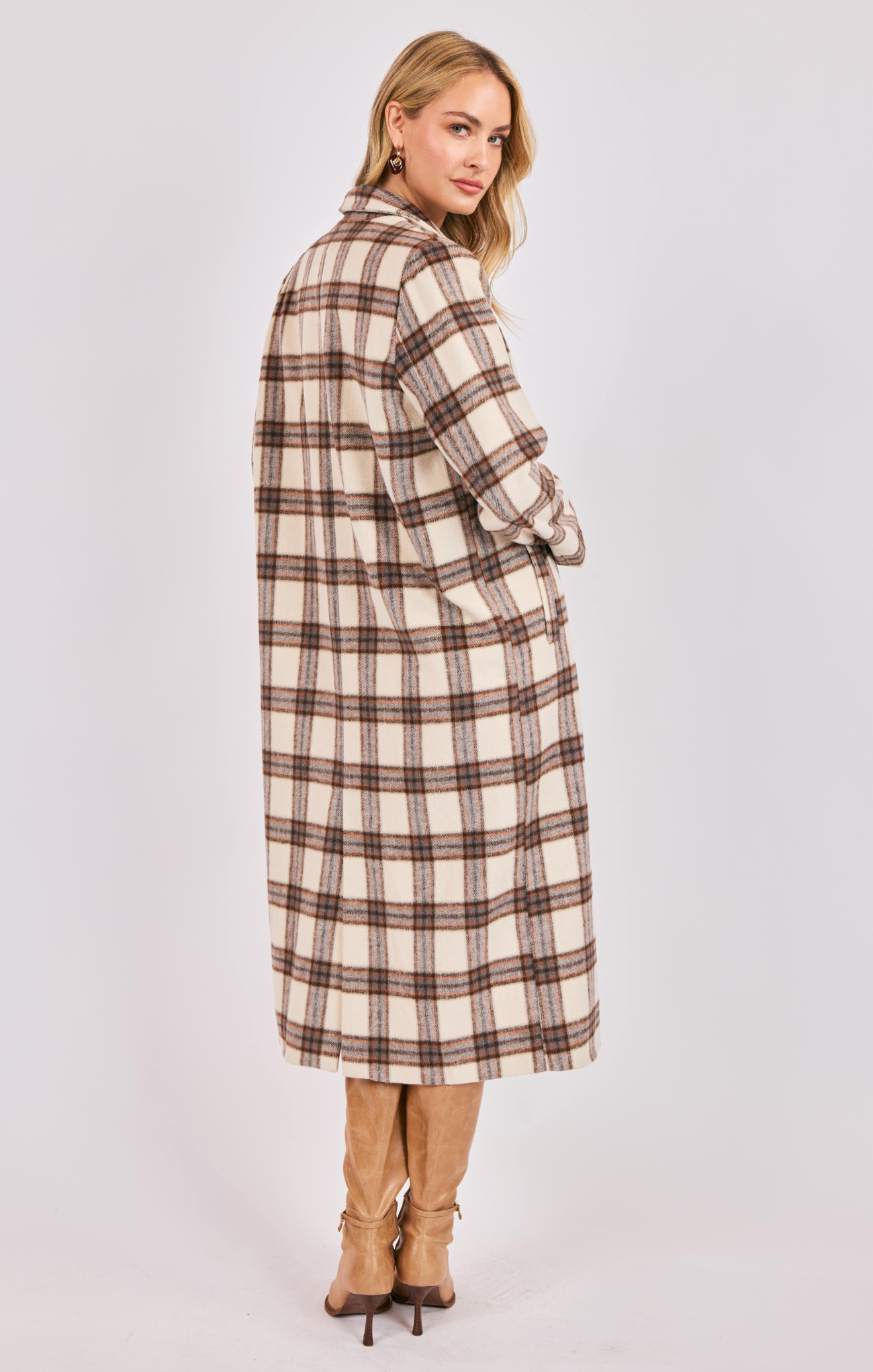 Woman wearing a long plaid coat on a white background