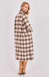 Woman wearing a long plaid coat on a white background