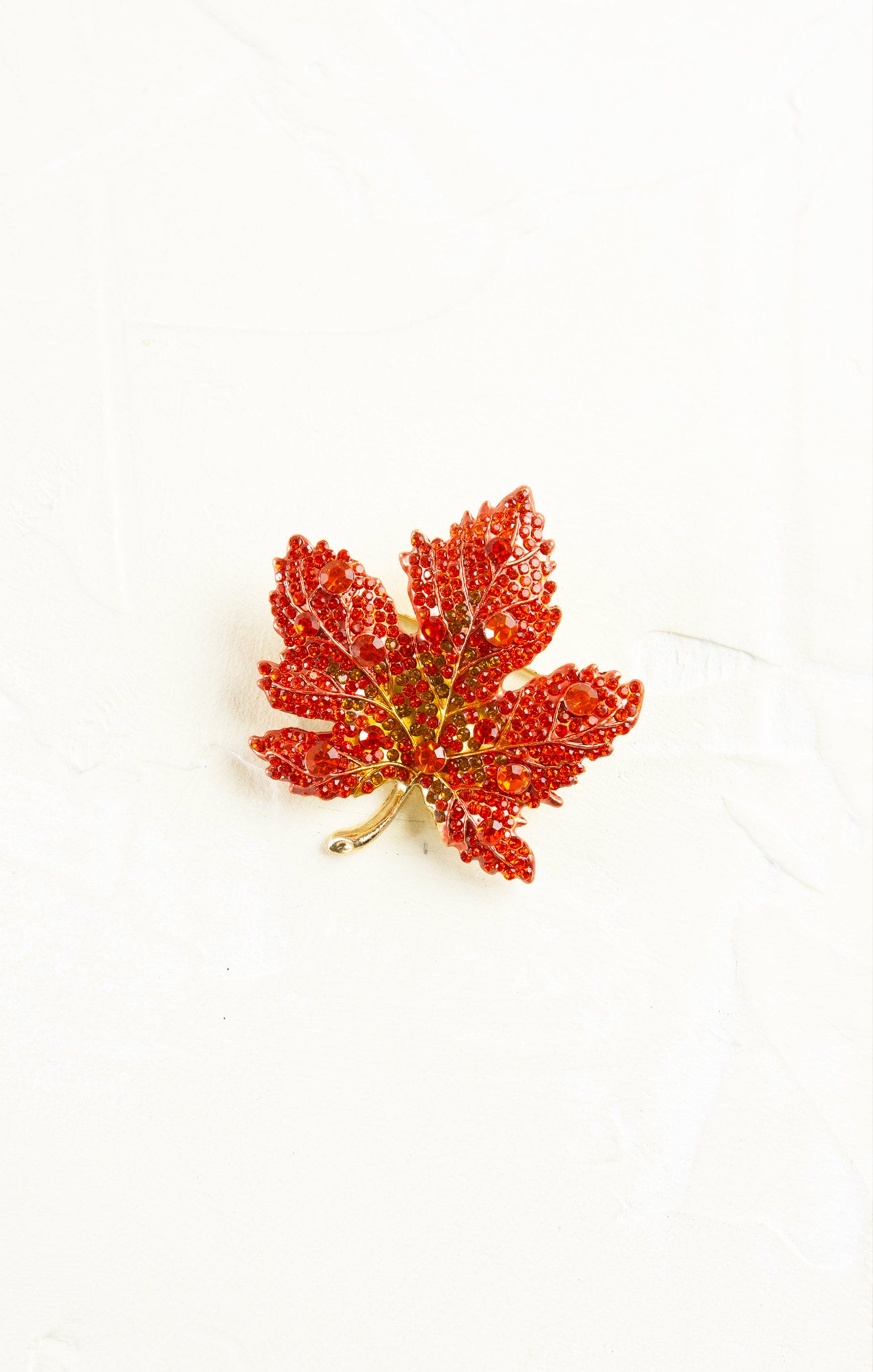 Red glittery leaf brooch on a white background