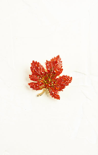 Red glittery leaf brooch on a white background
