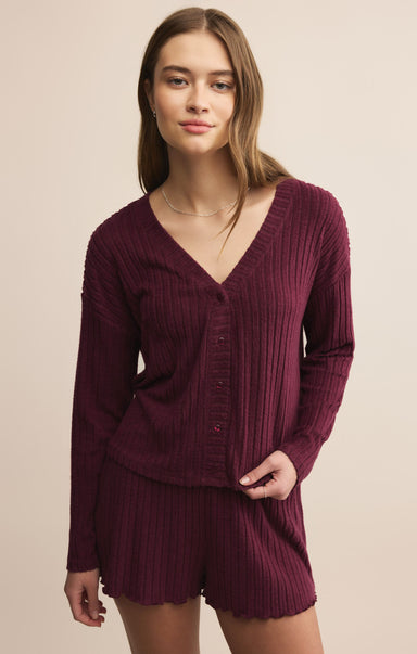 Woman wearing a burgundy ribbed sweater and shorts set on a beige background