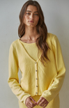 Woman wearing a yellow cardigan against a plain background