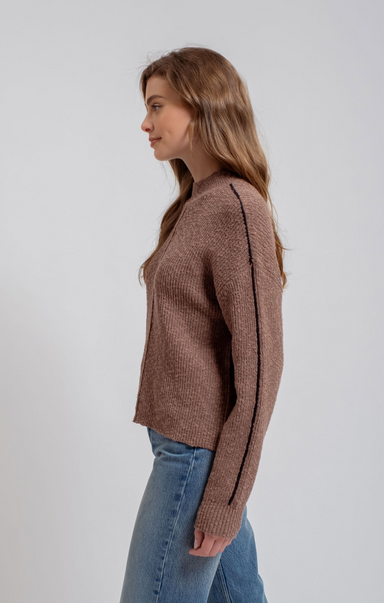 Woman wearing a brown knitted sweater and blue jeans on a white background