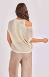 Woman wearing a beige knit top and beige pants on a light background