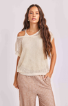 Woman wearing a beige crochet top and plaid pants on a white background