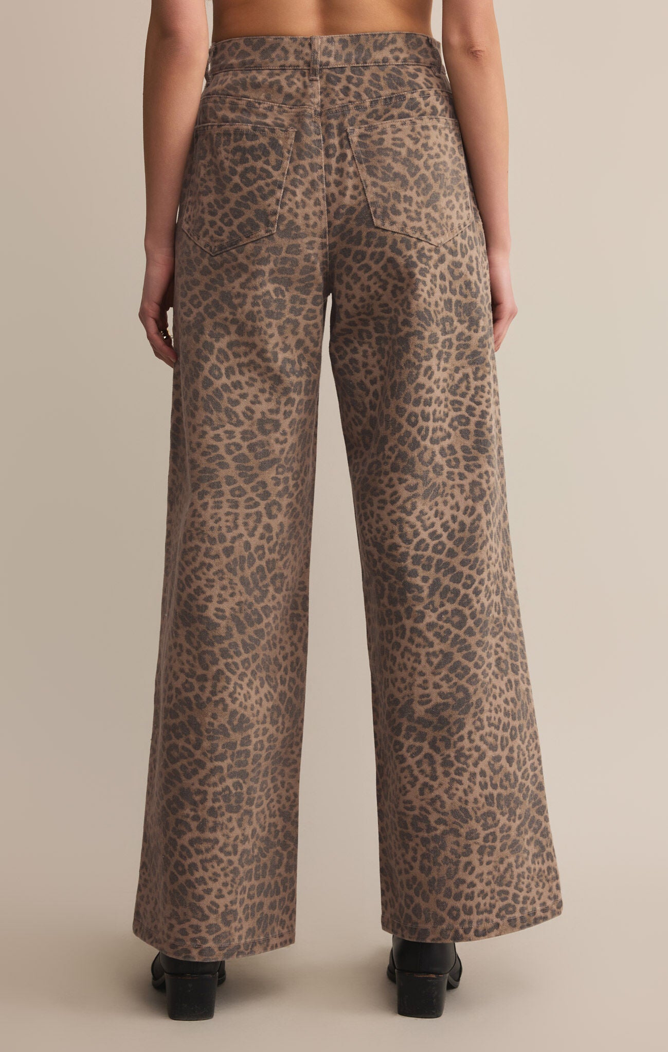 A pair of high-waisted, full-length leopard print denim pants with a zip fly and button closure.