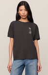 Person wearing a black t-shirt with a logo on a beige background