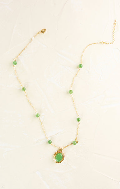 Gold necklace with green teardrop pendant on a white background