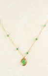 Gold necklace with a green pendant on a light background