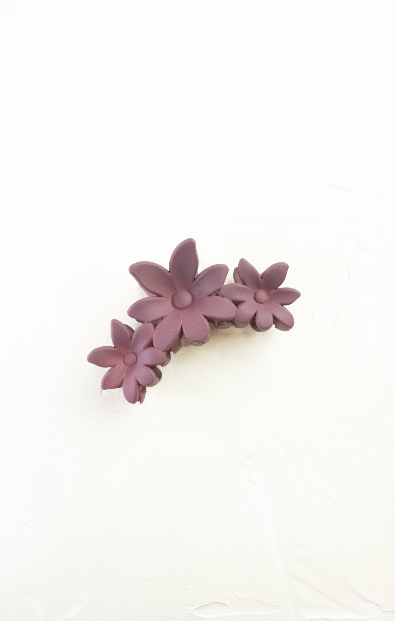 Purple flower-shaped hair clip on a white background