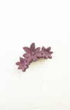 Purple flower-shaped hair clip on a white background