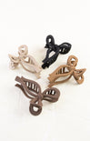 Set of four bow-shaped hair clips in beige, black, and brown on a white background
