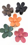 Set of five colorful flower-shaped hair clips on a white background