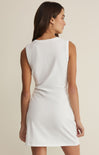 Woman wearing a white sleeveless dress against a beige background