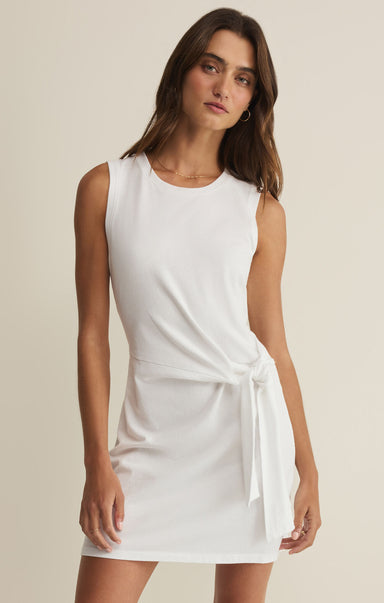 Woman wearing a white sleeveless dress against a beige background