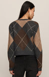 Person wearing a patterned sweater with a neutral background