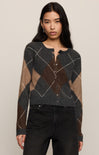 Woman wearing a patterned sweater and black pants on a plain background