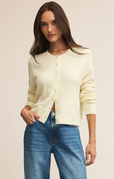 Woman wearing a light yellow cardigan and blue jeans on a beige background