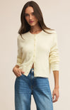 Woman wearing a light yellow cardigan and blue jeans on a beige background