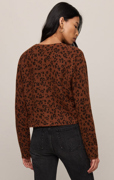 Woman wearing a brown leopard print sweater against a beige background