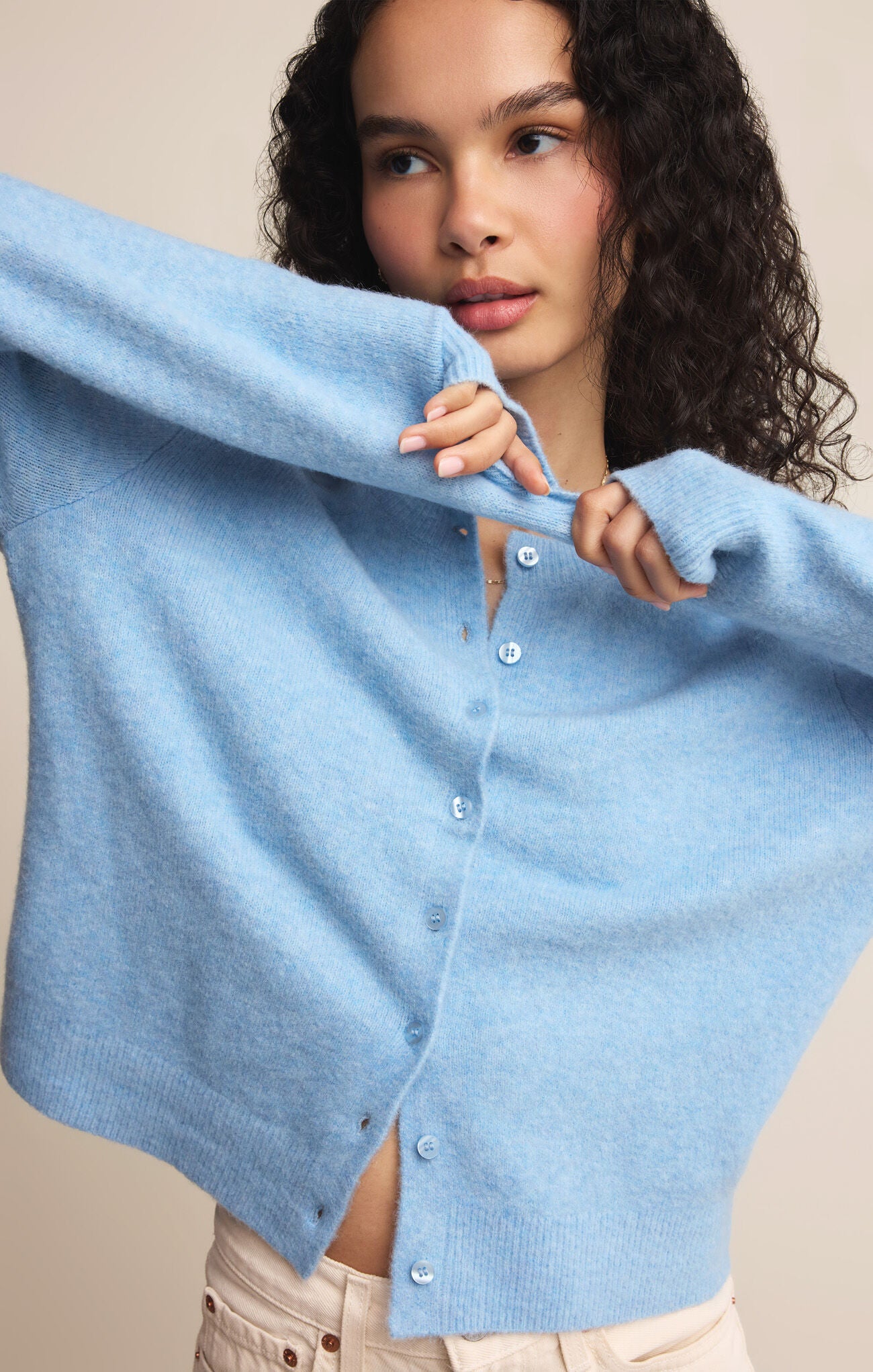 Woman wearing a light blue cardigan against a neutral background
