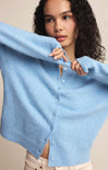 Woman wearing a light blue cardigan against a neutral background