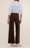 Person wearing a white shirt and brown corduroy pants on a beige background