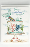 A square greeting card featuring a watercolor illustration of a mermaid-themed birthday cake on a pedestal stand. The cake is decorated with a blue mermaid tail, coral, a starfish, and a sea turtle, with the text 'happy birthday mermaid' written above in a light teal script.