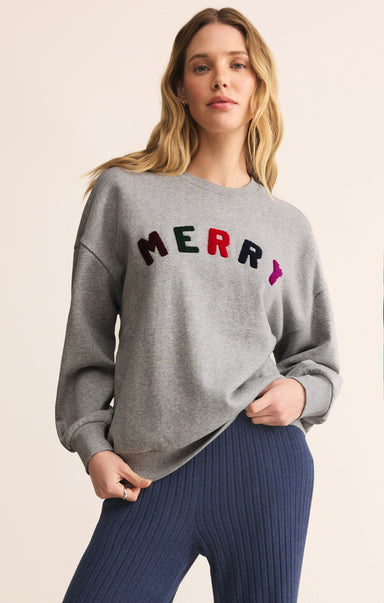 Woman wearing a gray sweatshirt with 'MERRY' in colorful letters on a beige background
