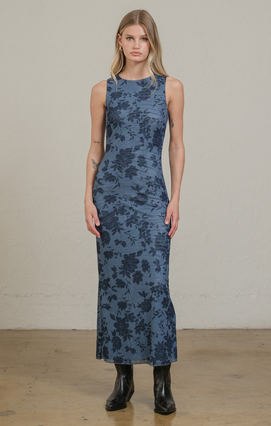 Woman wearing a blue floral dress against a plain background