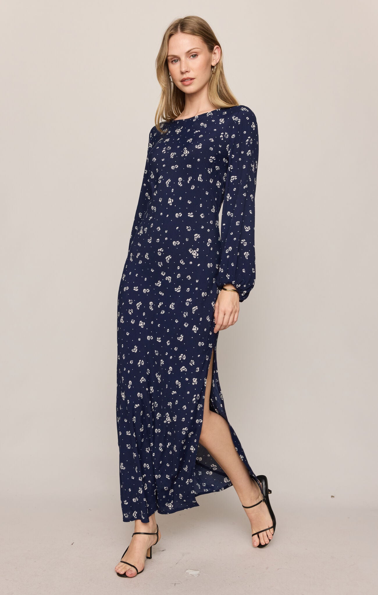 Woman wearing a navy blue dress with white floral pattern on a plain background
