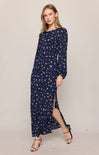 Woman wearing a navy blue dress with white floral pattern on a plain background