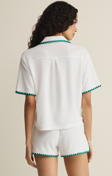 Woman wearing a white outfit with green trim on a beige background