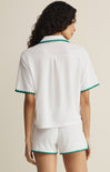 Woman wearing a white outfit with green trim on a beige background