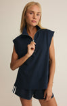 Woman wearing a navy sleeveless top with a zipper and shorts on a beige background