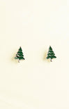 Green tree-shaped earrings on a beige background