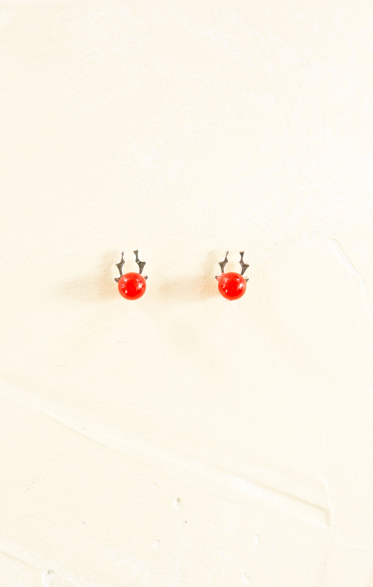 Small red earrings on a beige background