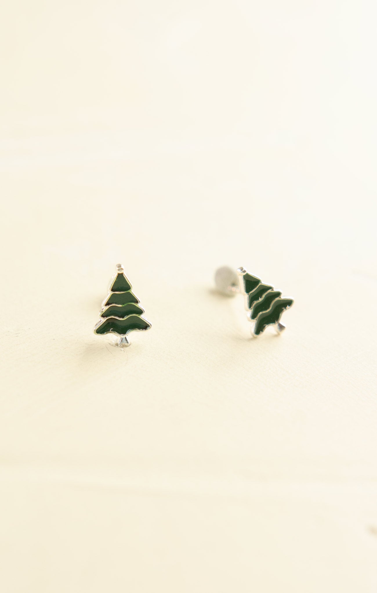 Green Christmas tree earrings on a beige background