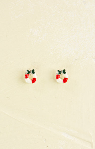 Small earrings shaped like Christmas wreaths on a beige background