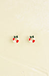 Small earrings shaped like Christmas wreaths on a beige background