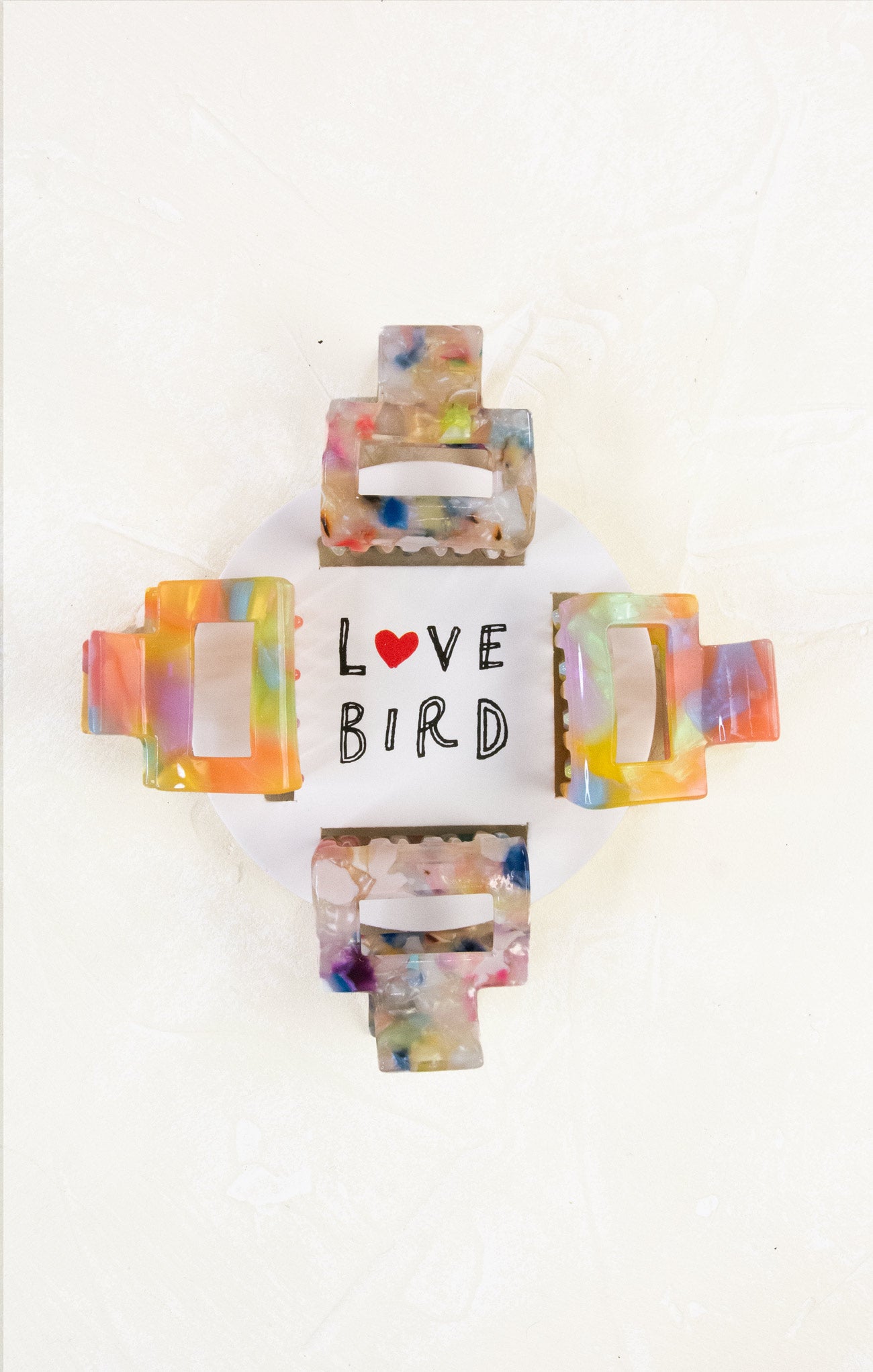 Colorful bird-shaped hair clip with 'LOVE BIRD' text on a white background