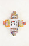 Colorful bird-shaped hair clip with 'LOVE BIRD' text on a white background