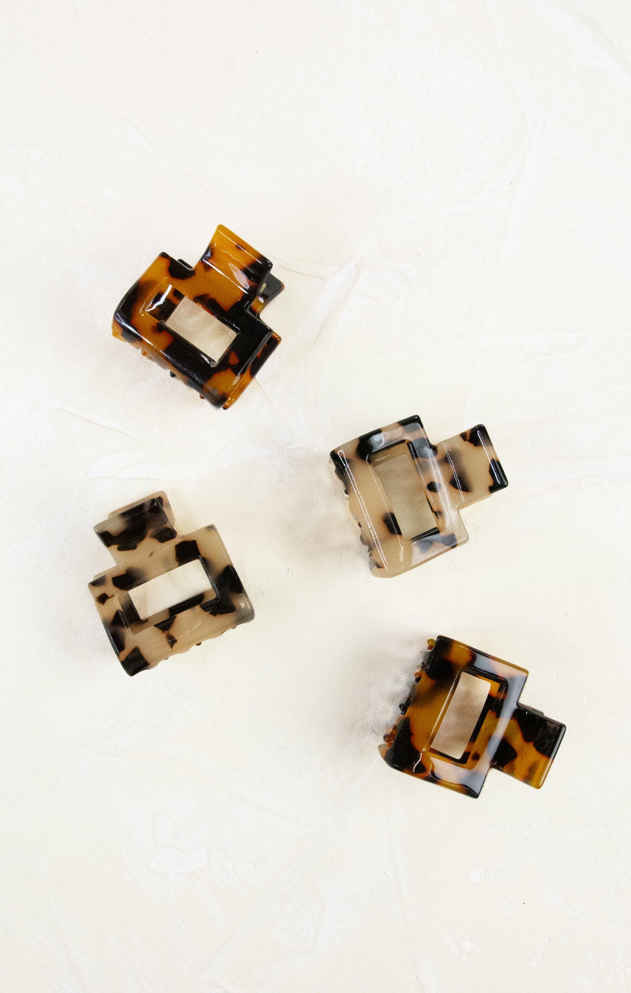 Four tortoiseshell hair clips on a white background