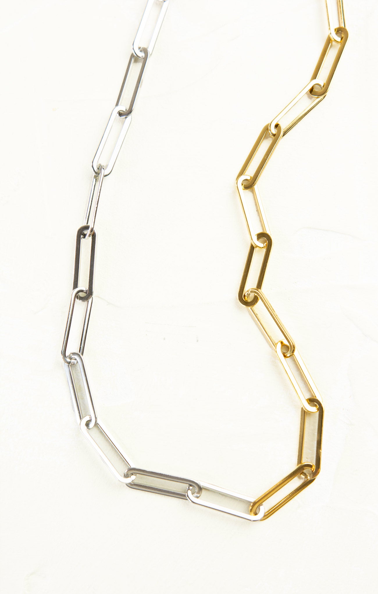 Two necklaces, one gold and one silver, on a white background